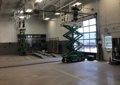 A large warehouse with two scissor lifts and a window.