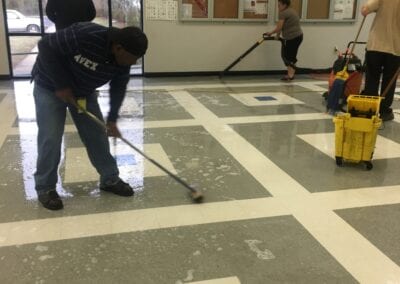 A group of people cleaning the floor in an office building.