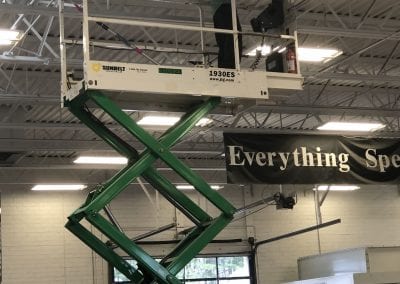 A man is on a scissor lift in an industrial building.