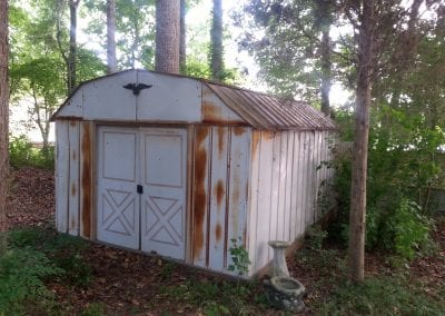 A white shed sitting in the middle of a forest.