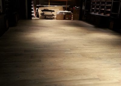 A wooden floor with lights on in the background.