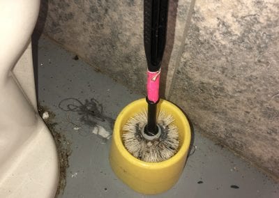 A yellow toilet bowl brush with pink handle.