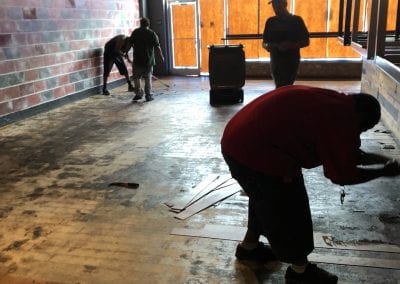 Three men working on a floor in an industrial building.
