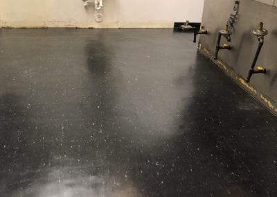A black floor with a sink and toilet in it
