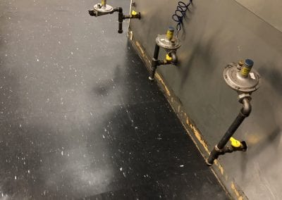 A black floor with some pipes and valves