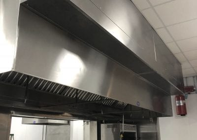 A large commercial kitchen with stainless steel hoods.