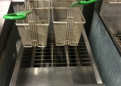 A stainless steel fryer with two baskets on top of it.