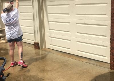 A woman is washing her garage door.