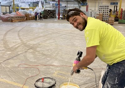 A man in yellow shirt painting a floor.